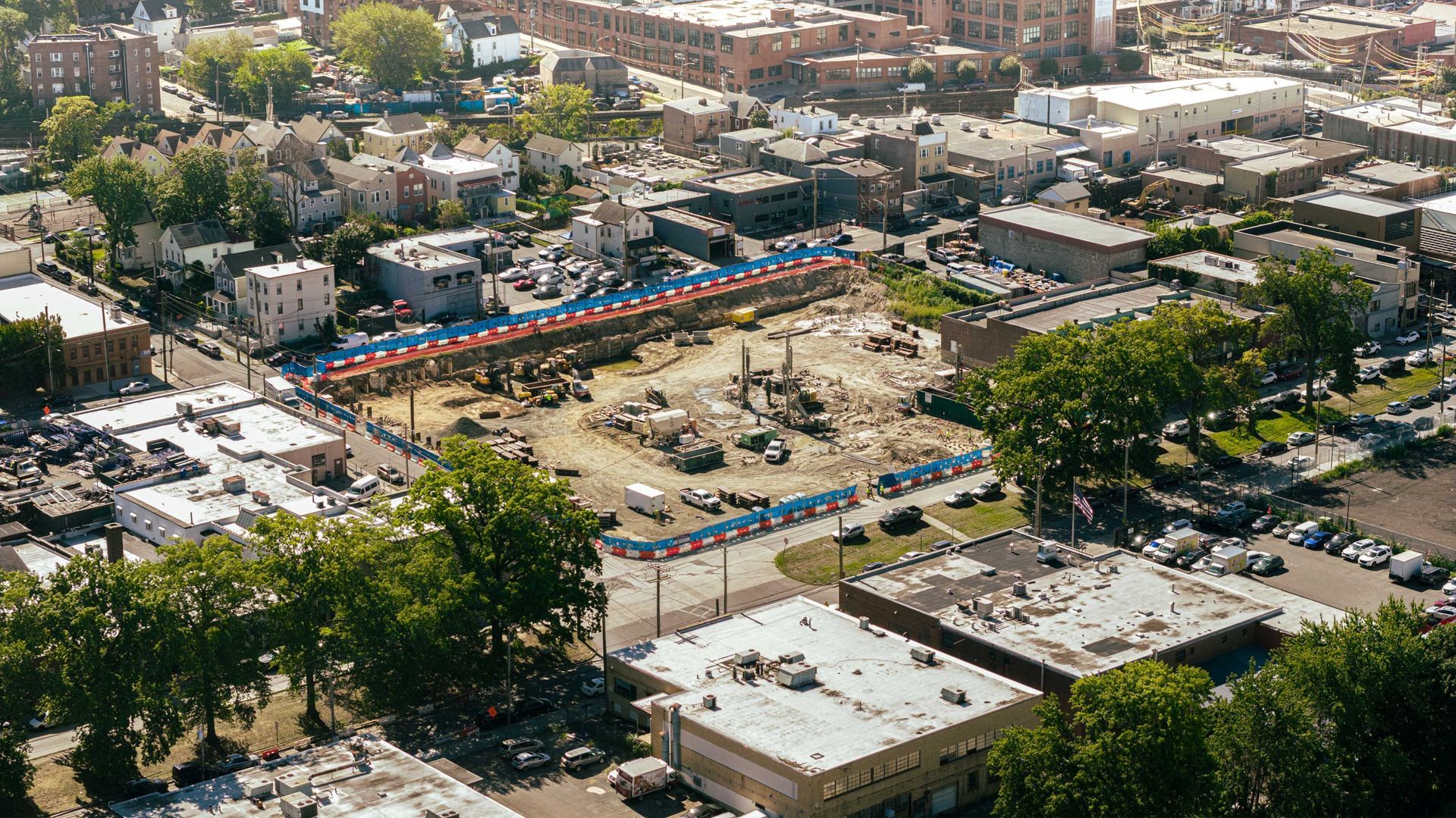 Aerial view of a construction site in a city, surrounded by buildings and trees.