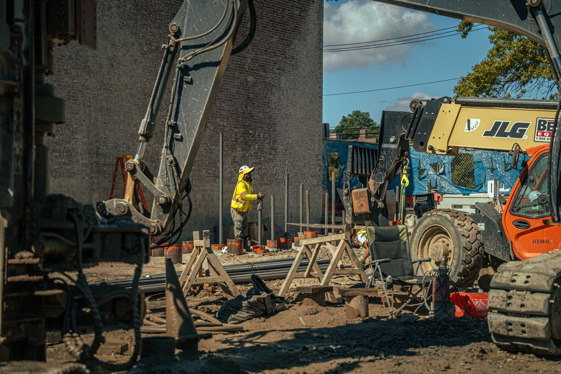 Construction site with excavator and worker in yellow vest.