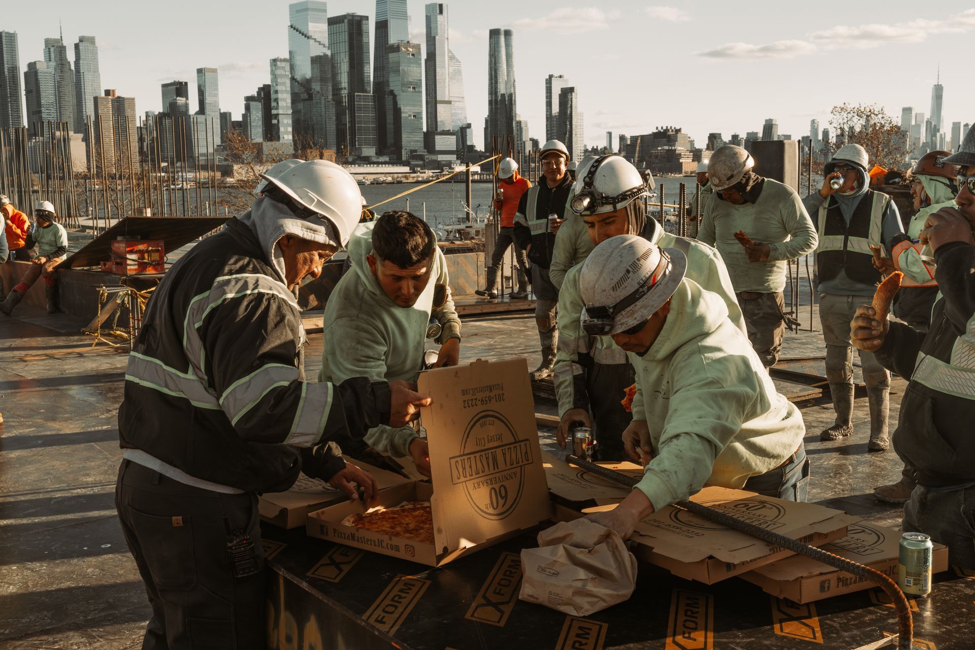 Workers in safety gear inspecting items on a table with a city skyline in the background.