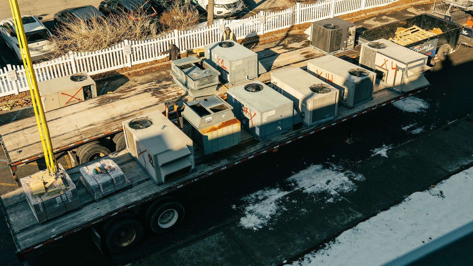 Truck bed loaded with several industrial air conditioning units, likely for transport.