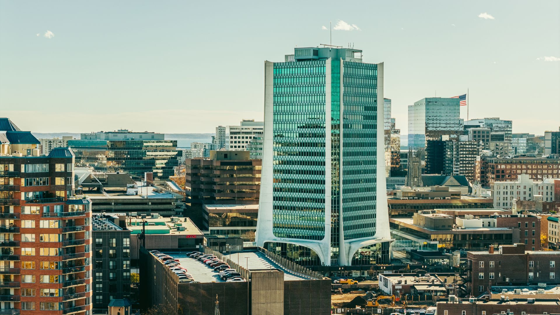 High-rise city buildings under a bright sky. Prominent tall building with green tinted windows.