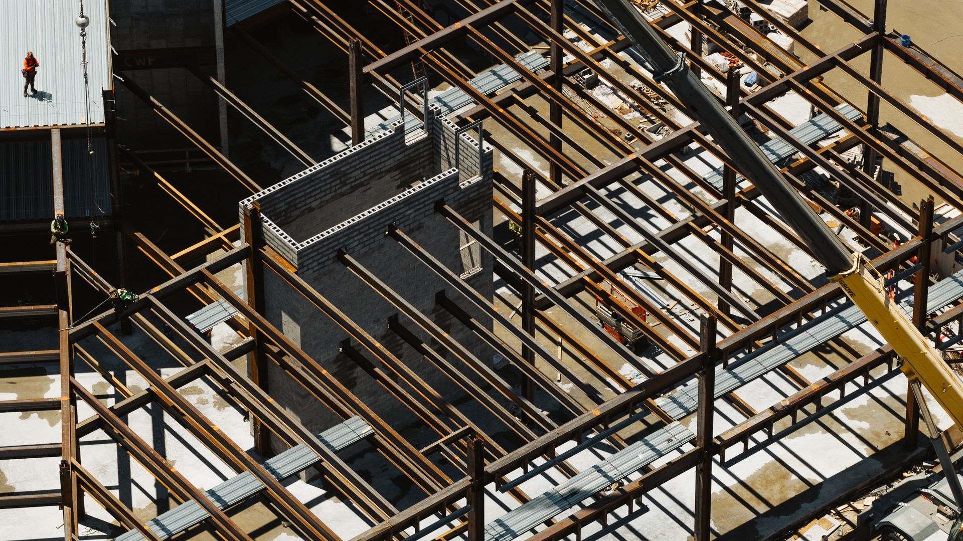 Steel beams framework for building construction. A yellow crane arm is visible.