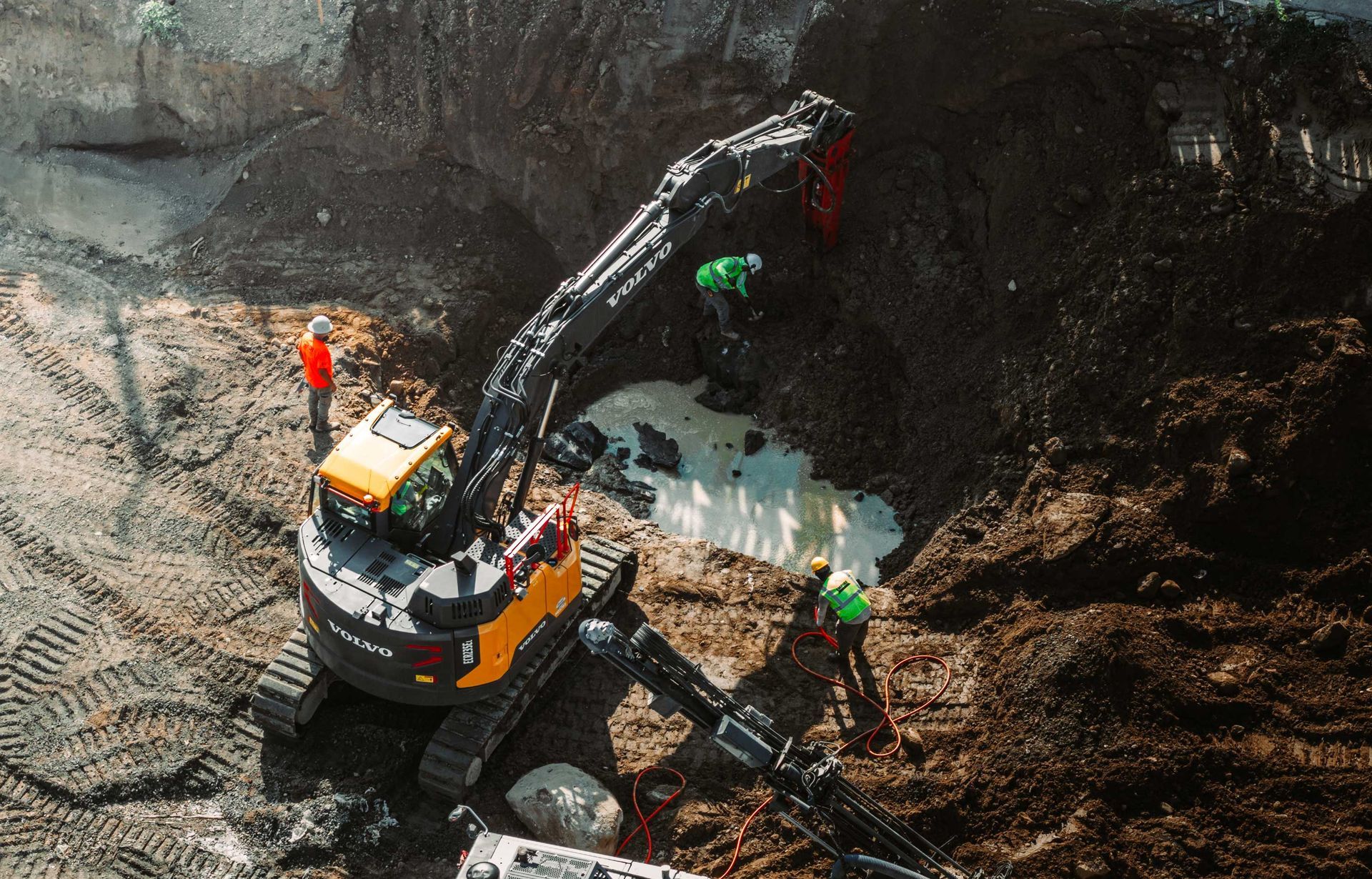 Excavator digging at a construction site. Workers in safety vests are present.