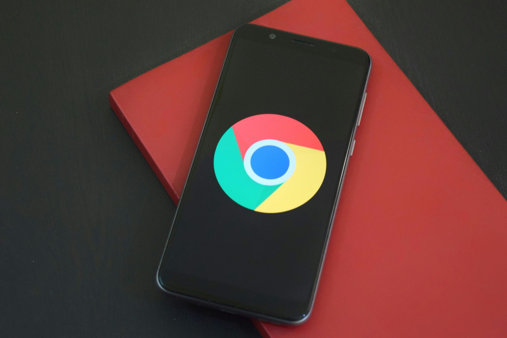 Smartphone displaying the Google Chrome logo on a red and black surface.