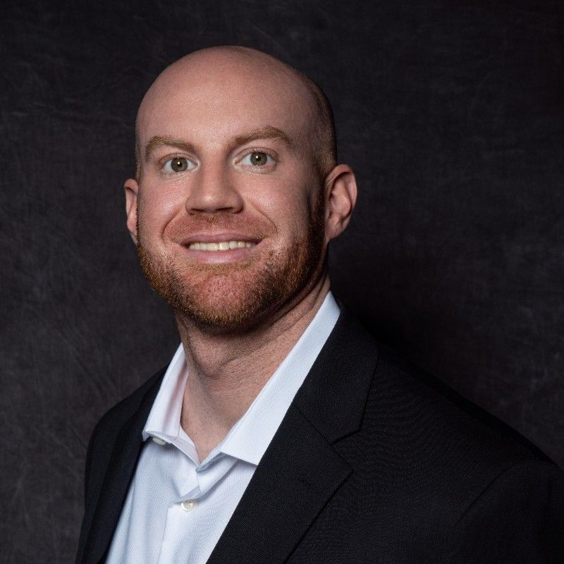 A bald man with a beard wearing a suit and white shirt