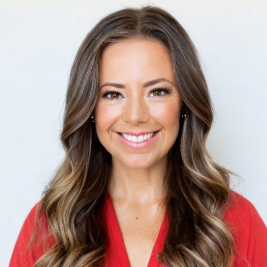 A woman with long hair is wearing a red shirt and smiling.