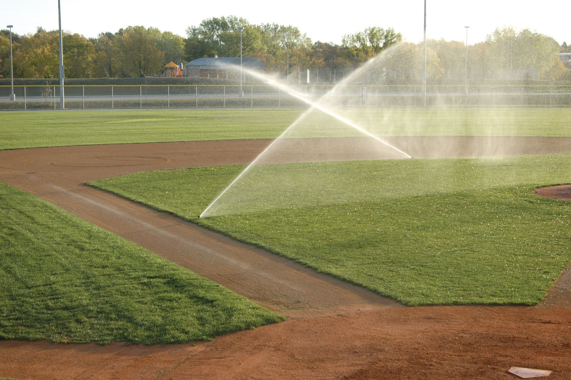 Baseball Field is Being Watered by a Sprinkler