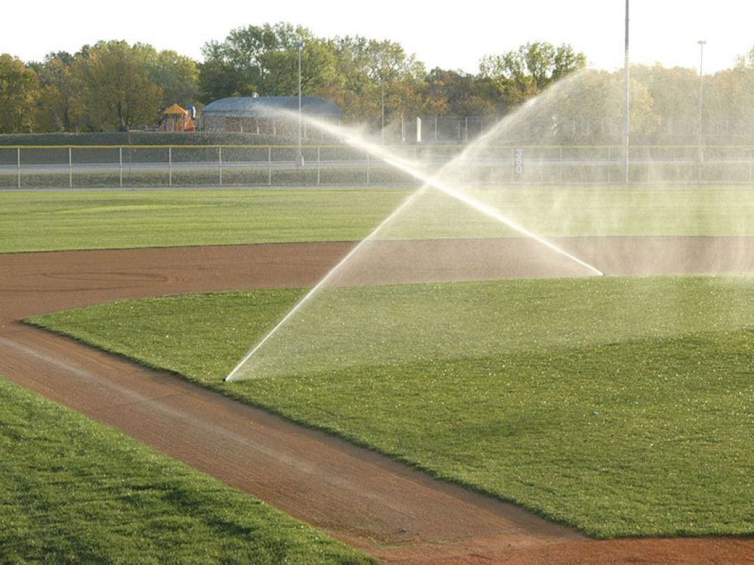 Baseball Field is Being Watered by a Sprinkler