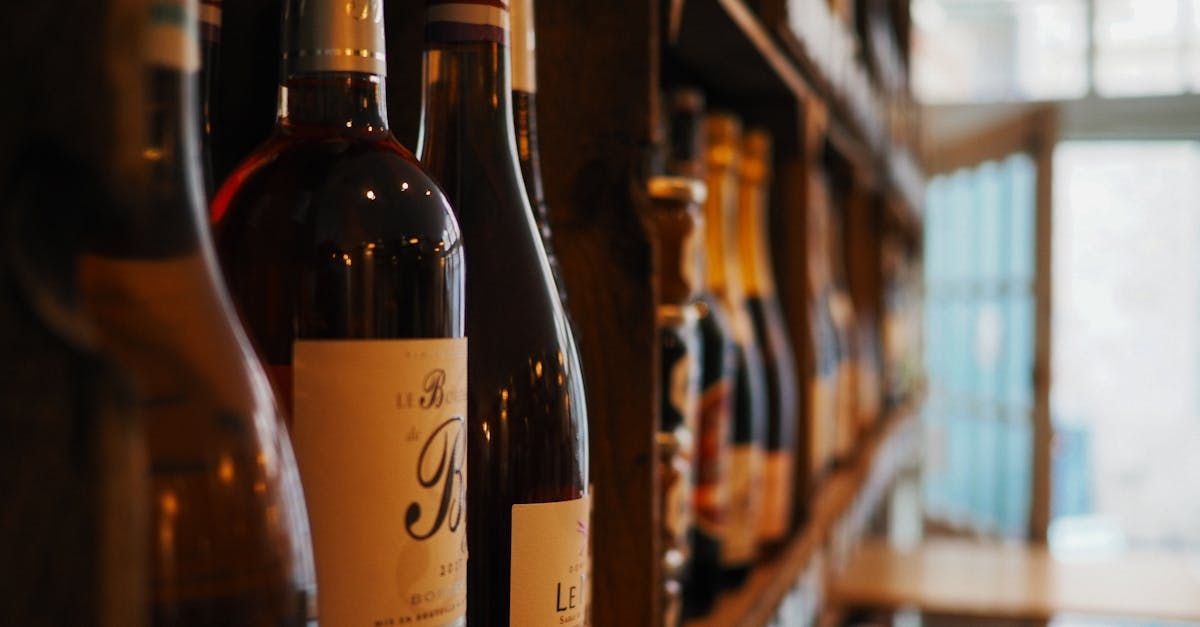 A row of wine bottles sitting on top of a wooden shelf.