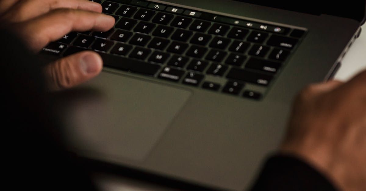 A person is typing on a laptop computer in the dark.