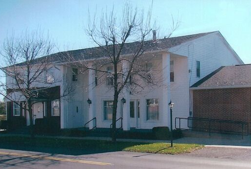 The front door of a house with a porch and plants in front of it.