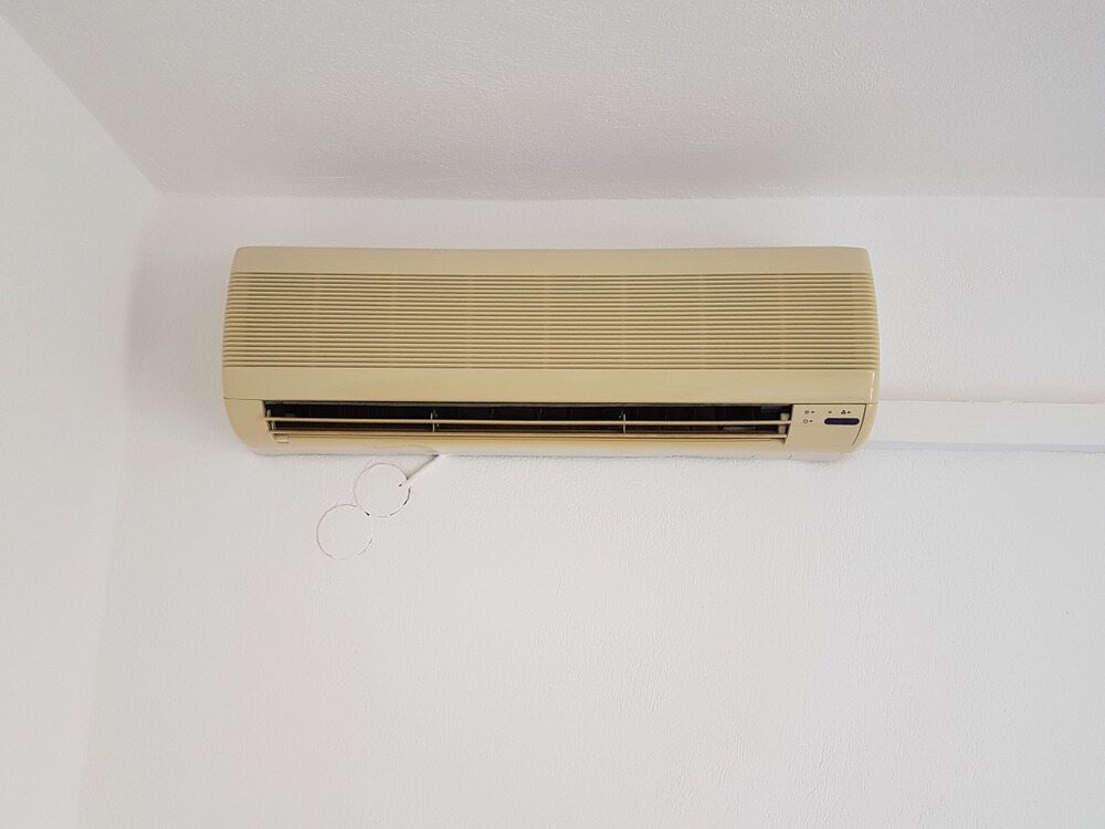 A Wall Mounted Air Conditioner Is Hanging On A White Wall — Bear Air Conditioning In Long Jetty, NSW