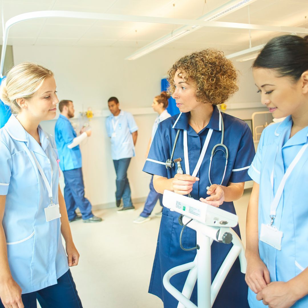 A group of nurses are standing in a room talking to each other