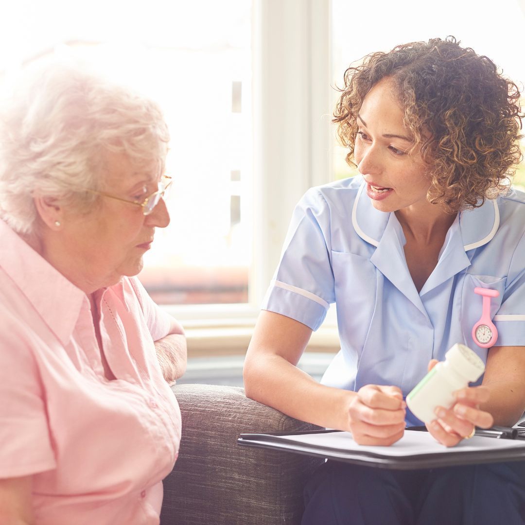 A nurse is talking to an older woman who is holding a bottle of pills.