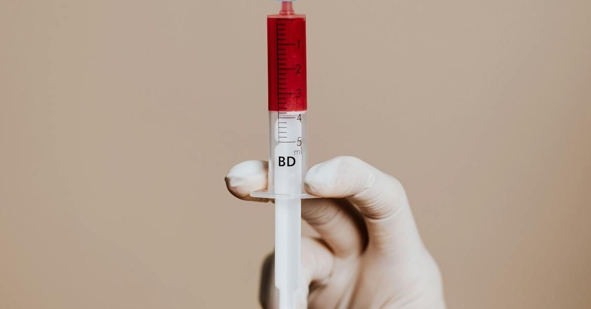 A person is holding a test tube with a red cap.