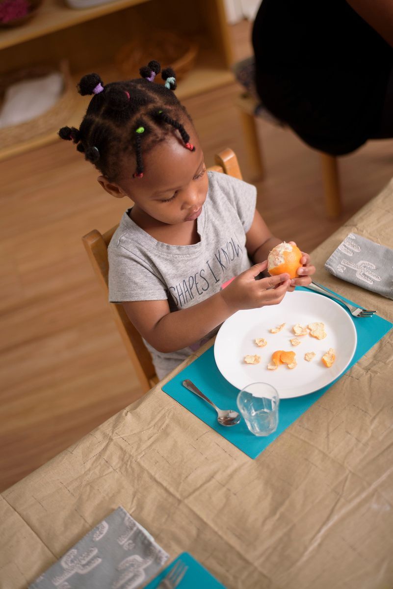 Child at a dining table lighting a birthday candle beside a plate of food