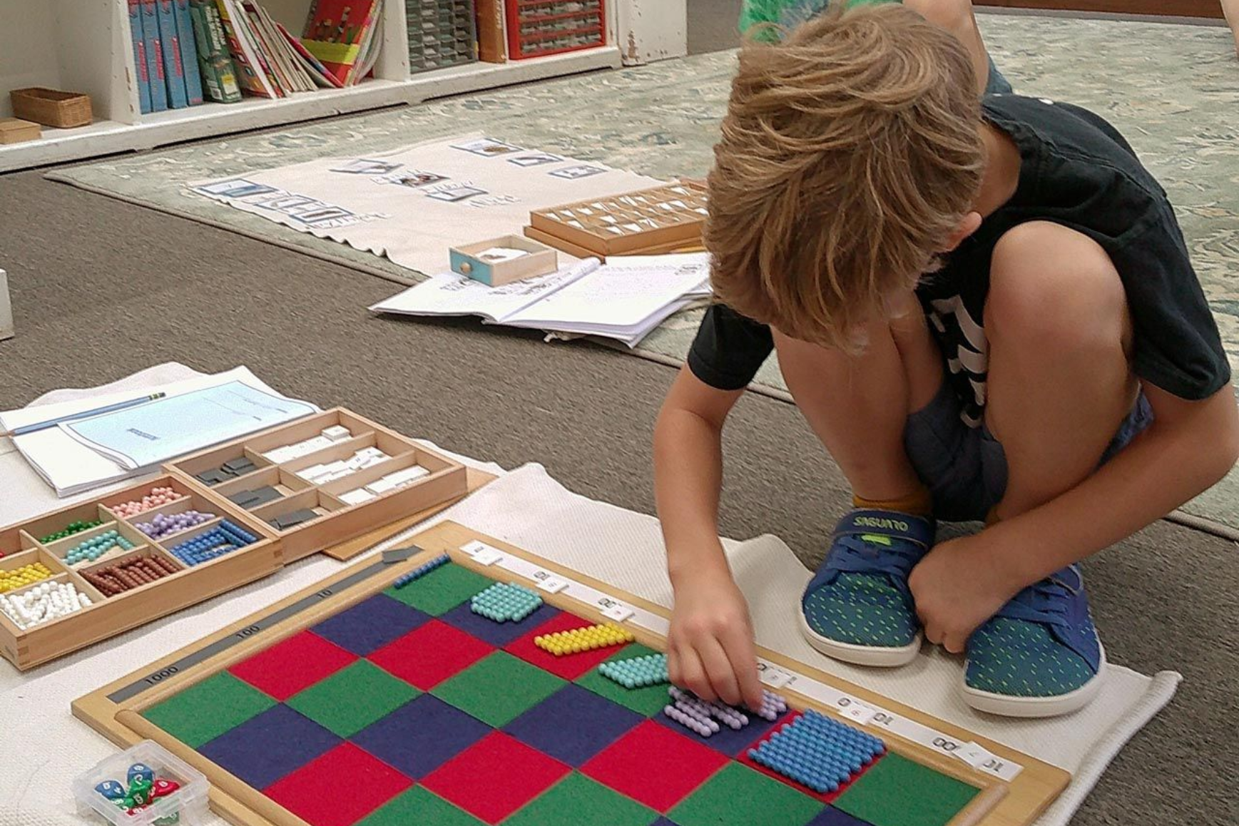 Montessori child calculating a multiplication problem using the Checkerboard material