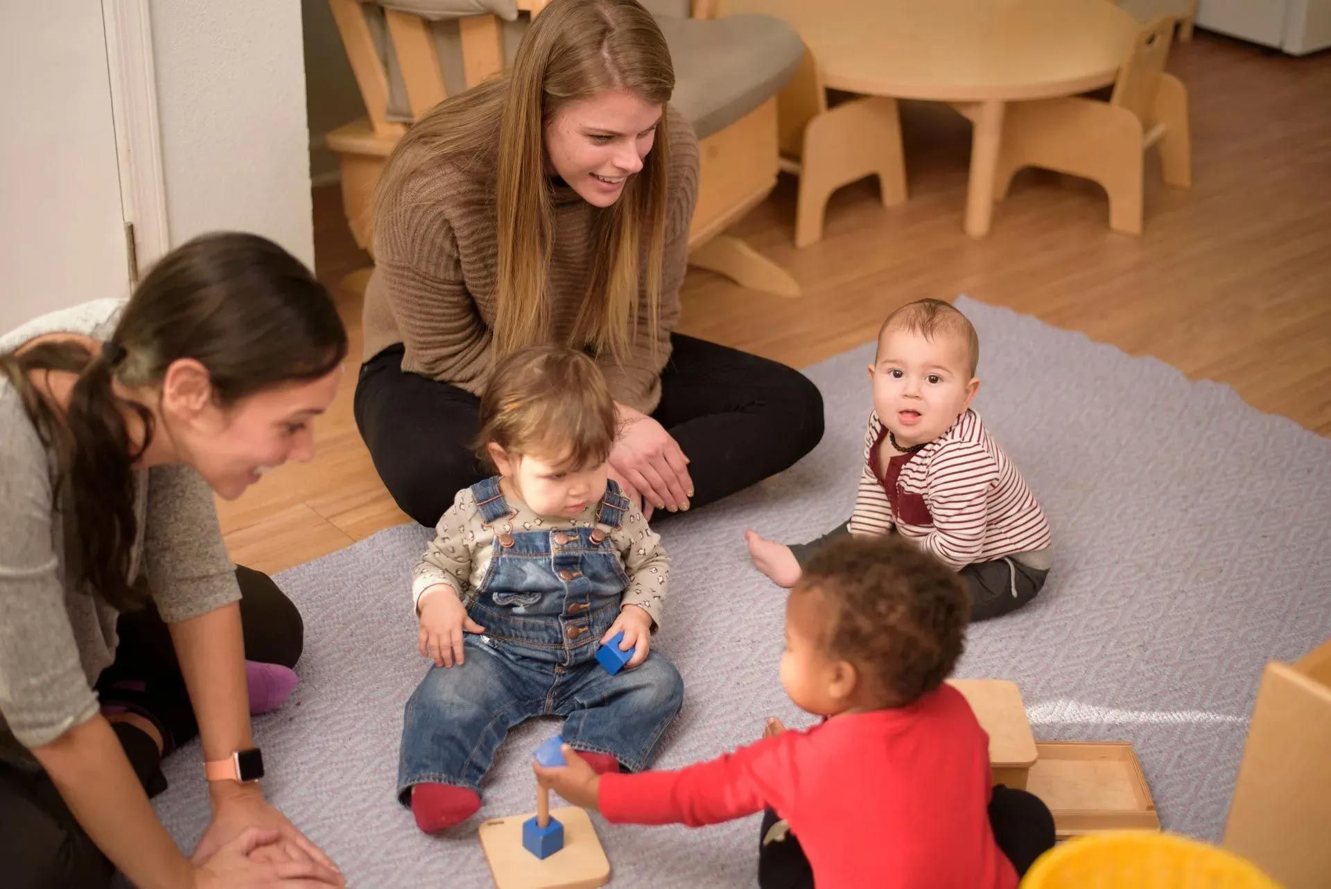 Infants and guides working with Montessori materials on the floor. 