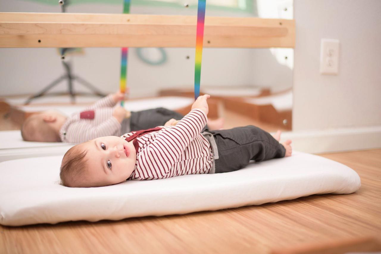 A Montessori Infant is laying on a mattress in the classroom.