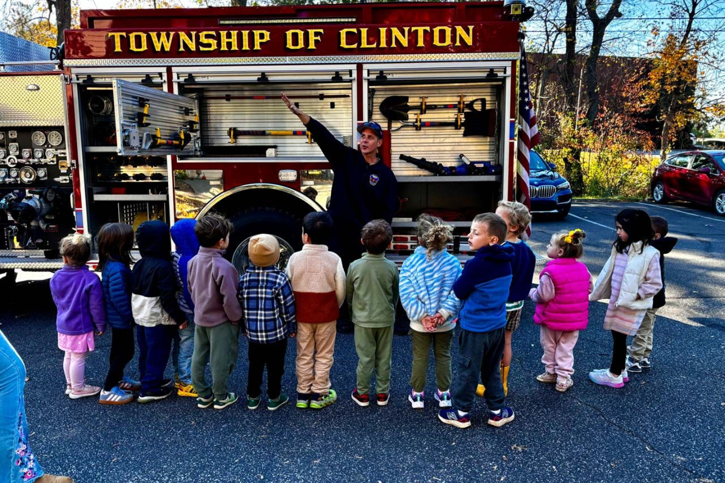Montessori primary children listening to a firefighter next to a fire truck