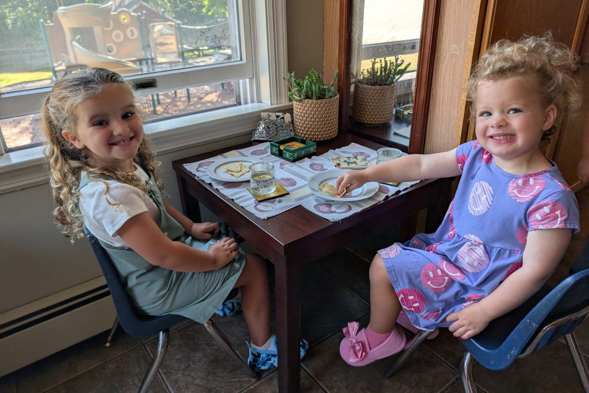 Montessori primary children smiling while eating snack at a small table