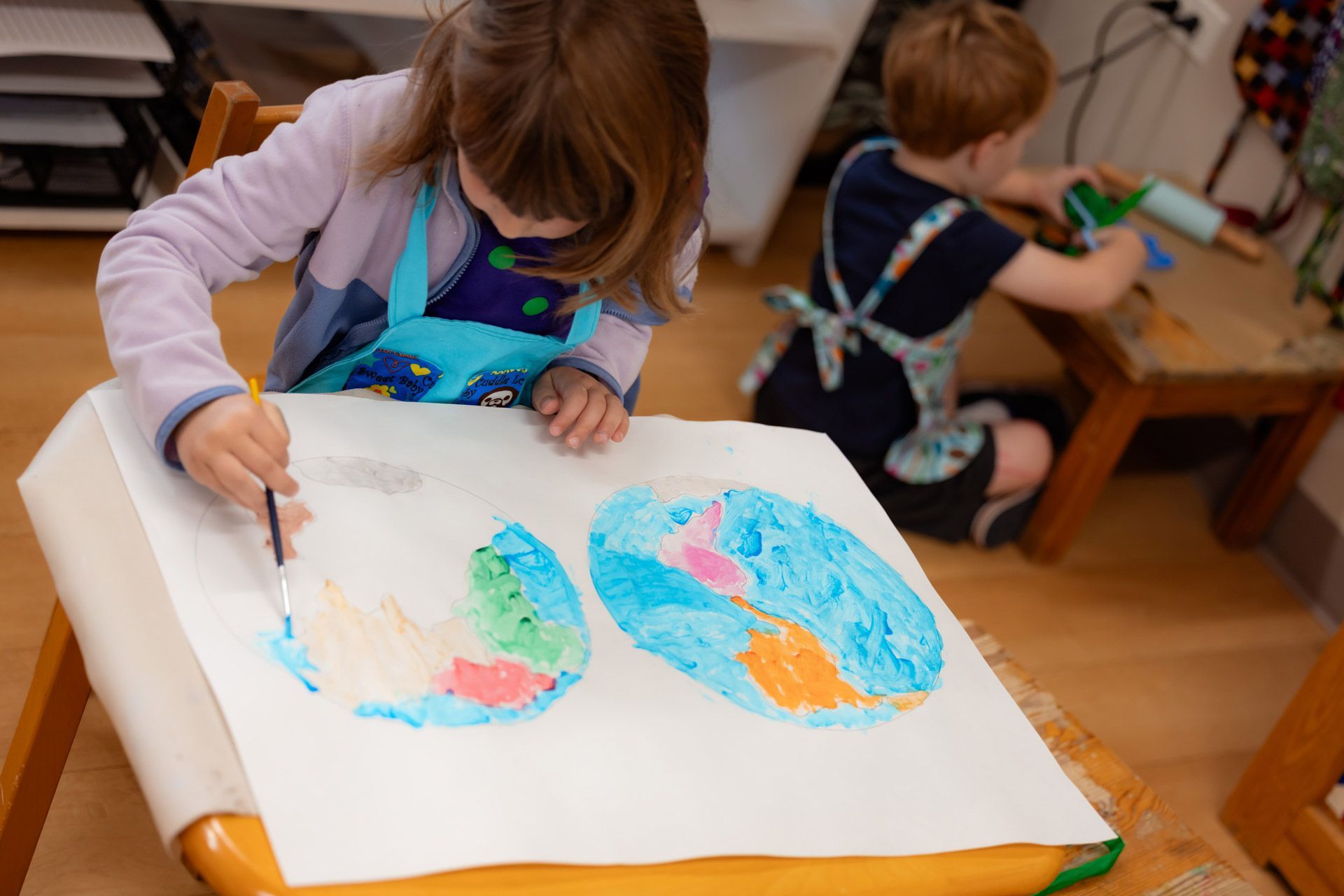 A Montessori primary student carefully painting a world map with watercolors 