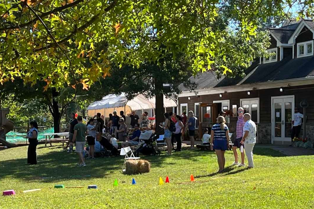 Parents and staff participating in a community social event at a Montessori school, featuring outdoor seating and a spacious campus environment