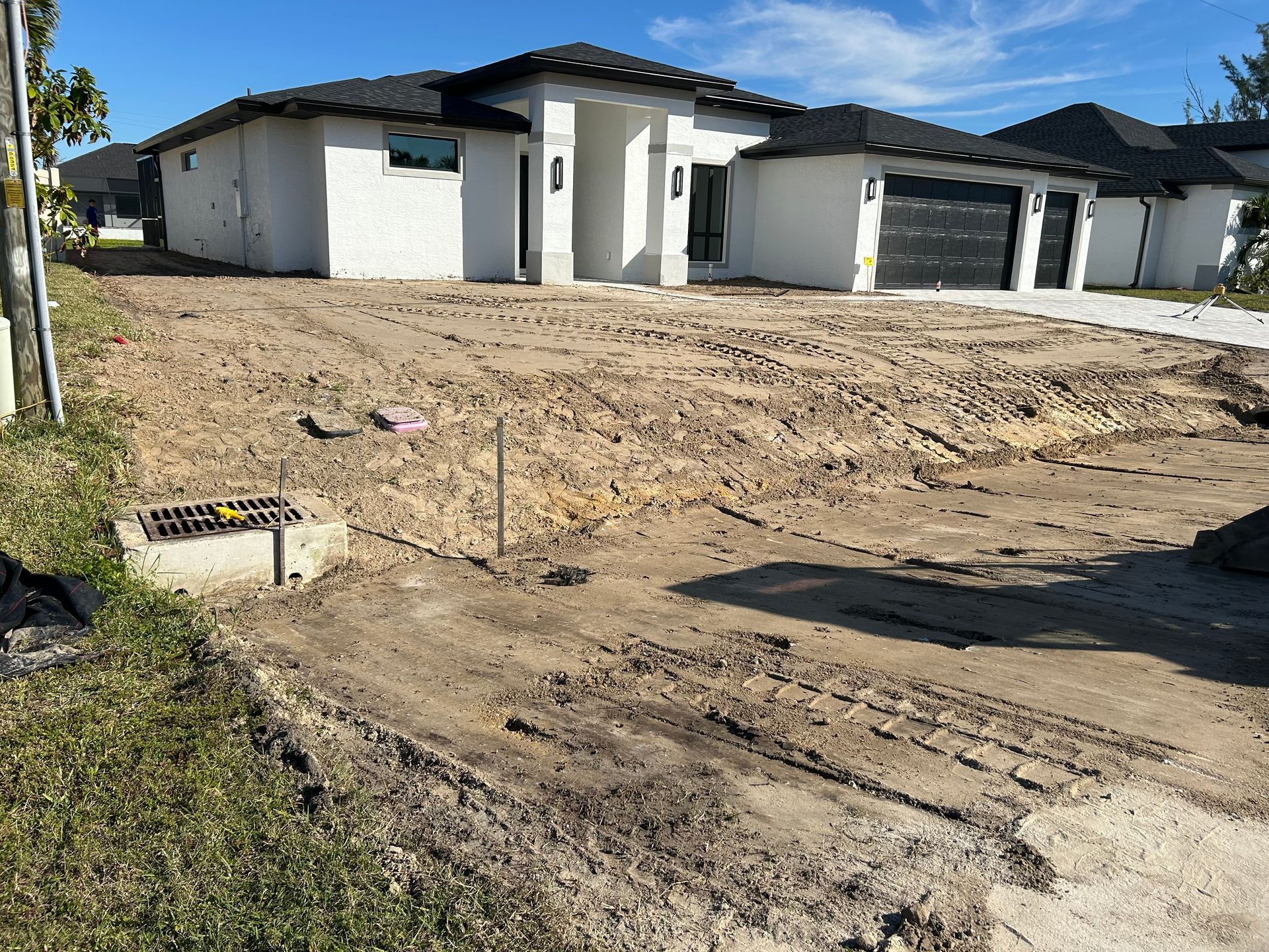 House under construction; dirt yard, storm drain, tire tracks.