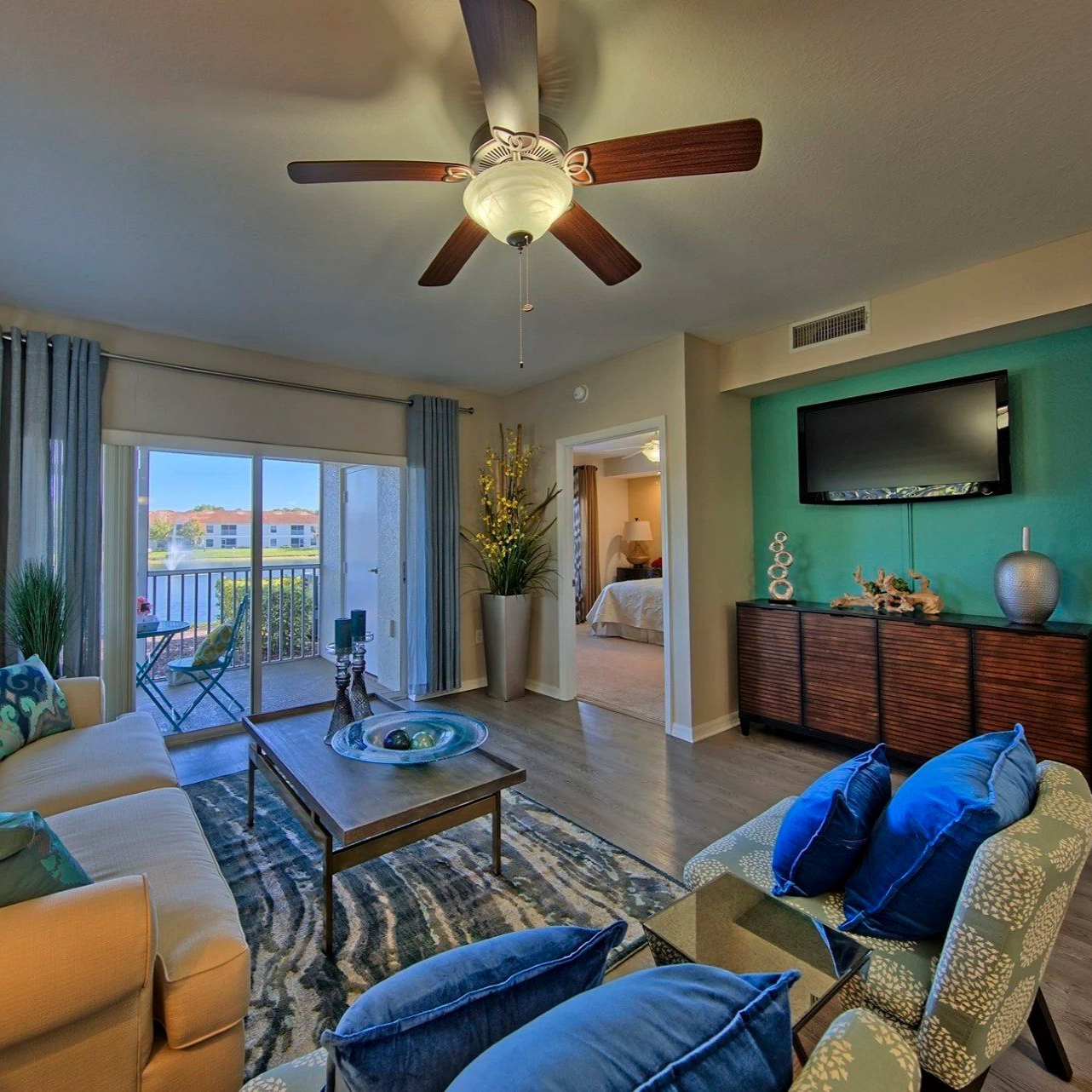 Living room with blue and beige decor, open to a balcony with lake view.