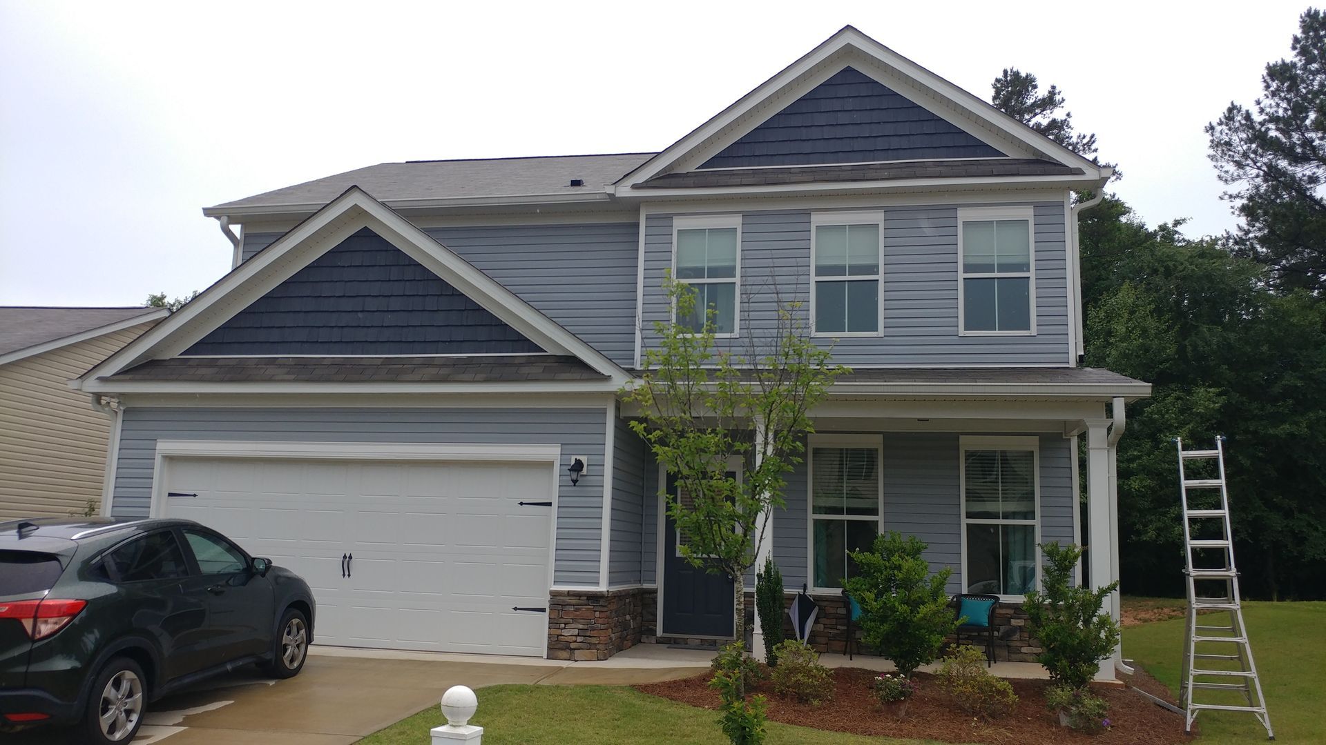 Two construction workers standing in front of a modern townhome under construction.