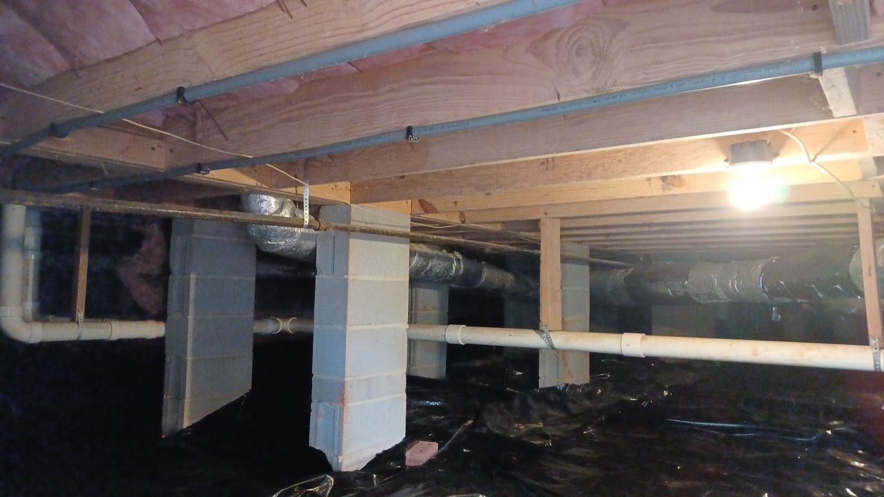 Man in a dust mask inspecting a crawl space with a flashlight.