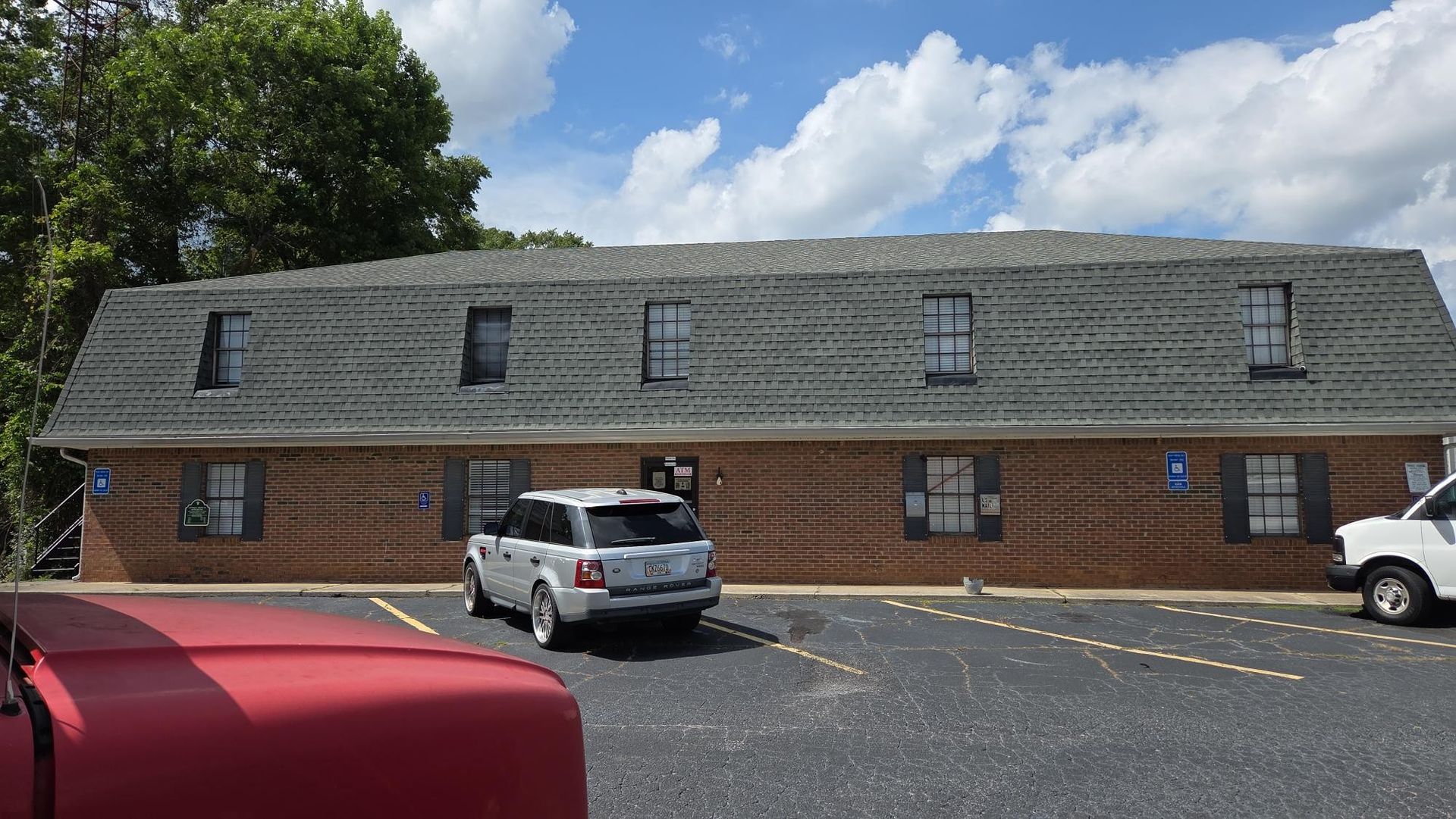 Two construction workers stand outside new townhouses with brick and green accents.