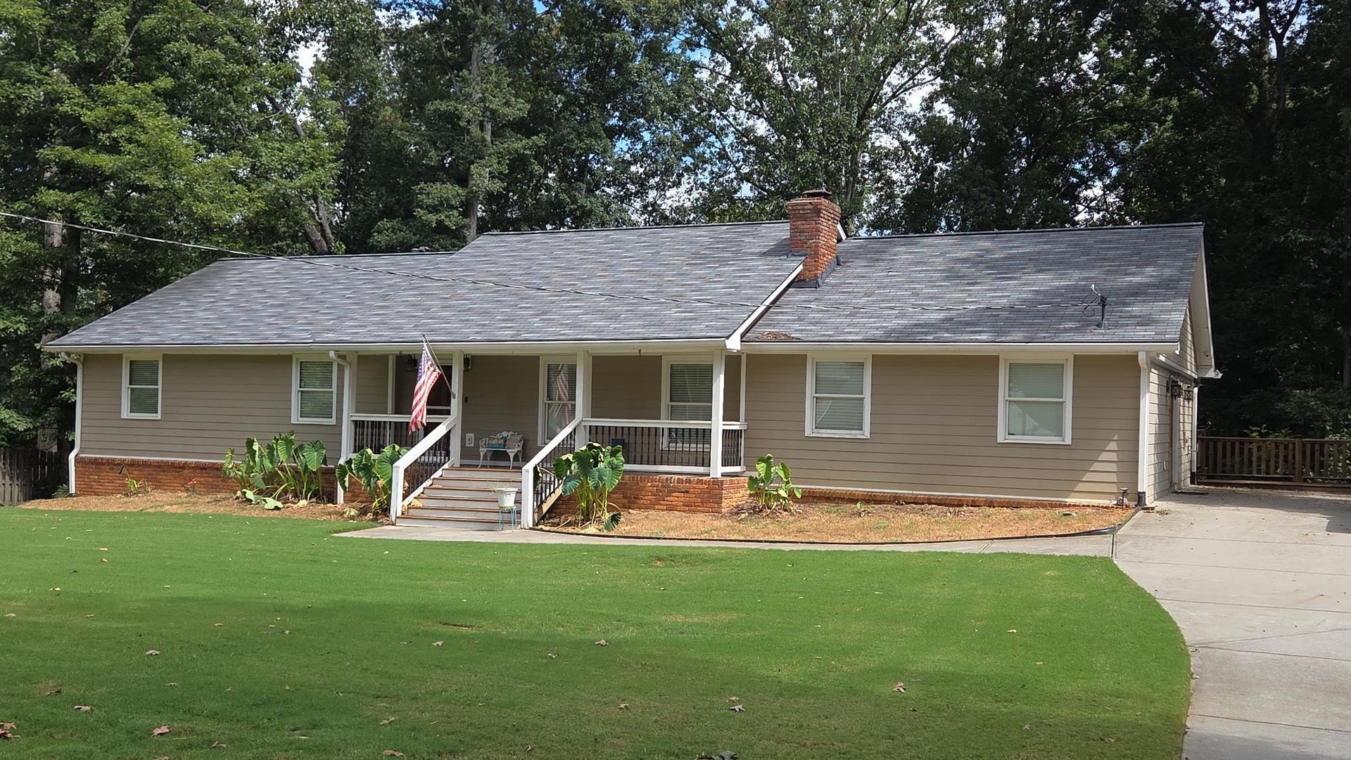 Hand holding keys above a person signing a document, miniature houses, and a calculator on a table.