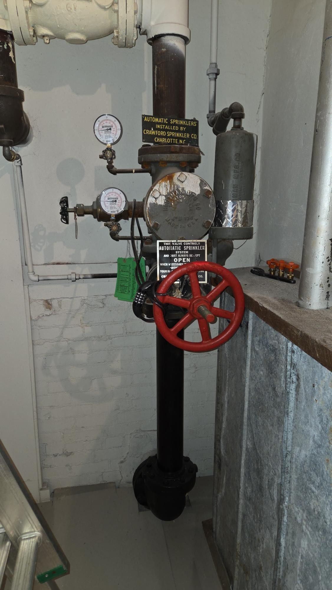 Man in a hard hat working on HVAC ductwork, using a tool. Industrial setting.