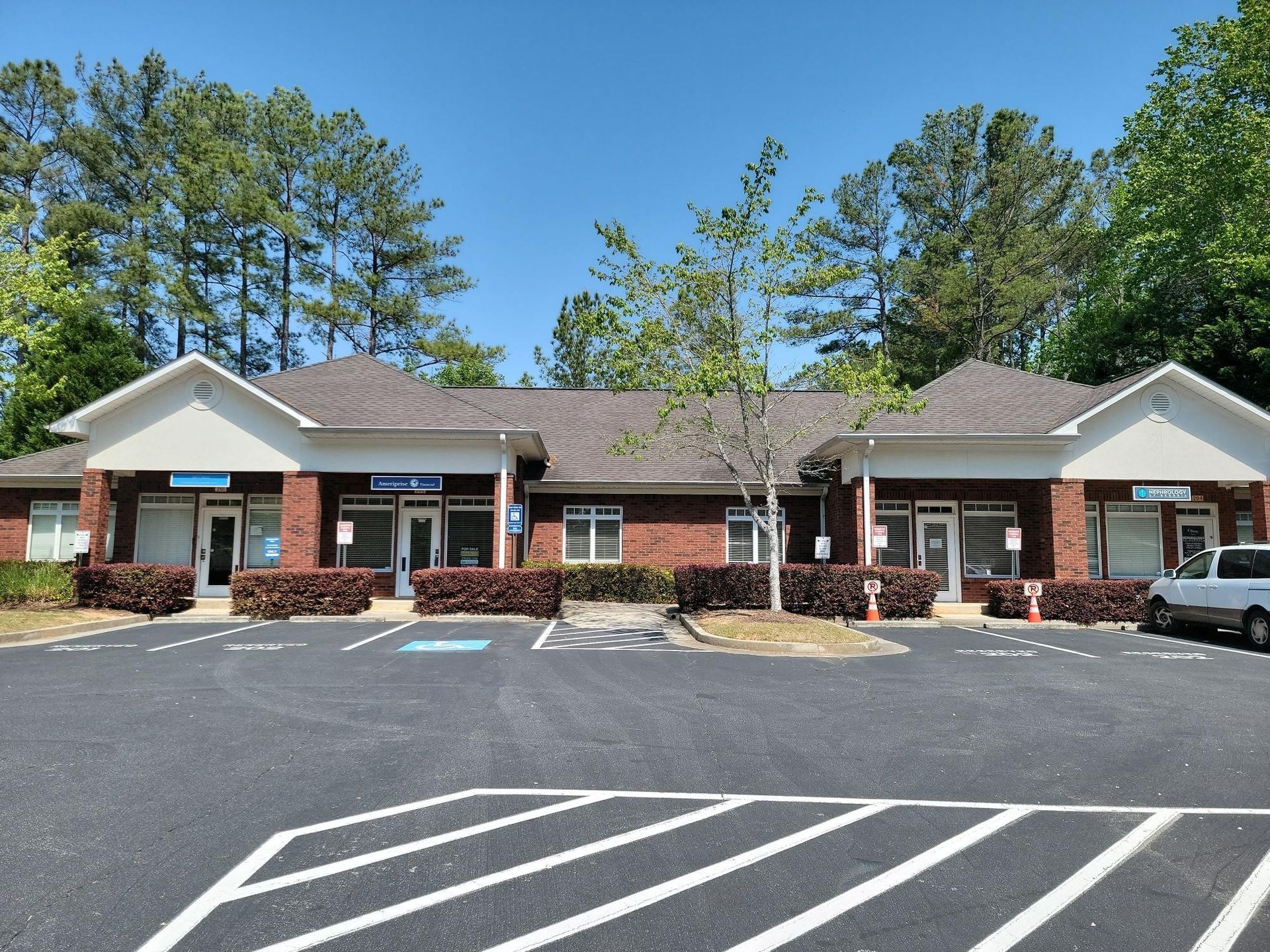 Red brick commercial building with multiple storefronts and a parking lot.