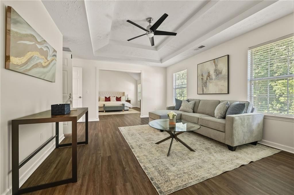 Living room with gray sofa, rug, glass coffee table, and dark wood flooring.