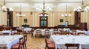 Elegant banquet hall with chandeliers, patterned carpet, and tables set with white tablecloths and chairs