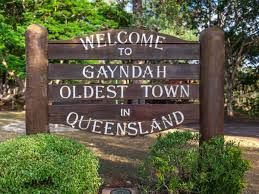 Wooden welcome sign reading “Gayndah, oldest town in Queensland” amid greenery