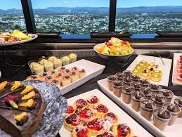 Dessert buffet with pastries and chocolate cups overlooking a city through large windows