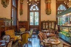 Elegant cafe interior with ornate wood paneling, vintage chairs, and a display case.