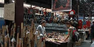 Market stall with handcrafted goods, two people browsing.