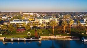 Aerial view of buildings, palm trees, and waterfront.