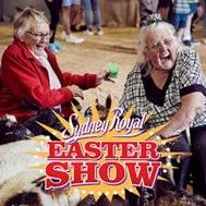 Two older women laughing at the Sydney Royal Easter Show. One holds green prize.