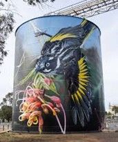 Mural of a black and yellow bird with a floral arrangement painted on a grain silo.