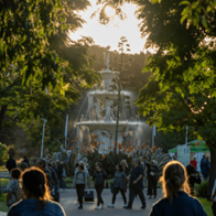 Fountain in a park with people, trees, and sunlight.