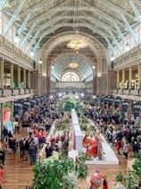 Grand indoor hall, filled with people. Long central displays, arched ceiling.