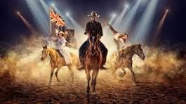 Cowboy show with riders on horses under bright lights.