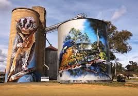 Two silos with paintings of animals and birds on them.