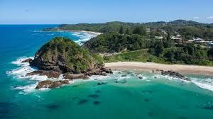 An aerial view of a beach with a cliff in the middle of the ocean.