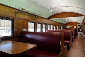 The inside of a train car with red benches and tables.